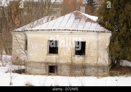 verlassene alte Mauerwerk Ziegelhaus mit zerbrochenen Fenstern in der Nähe von lebendigen Haus Bezirk im Winter. Stockfoto