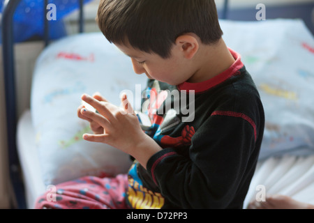 Junges Mädchen spielt Spiele auf Handy im Bett Stockfoto