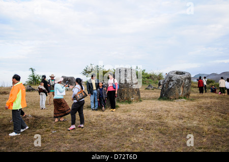 Eine Familie posiert für Fotos unter die steinerne Krüge auf Seite 1 von Plain of Jars in Nord-Zentral-Laos. Viel ist über das Alter und Zweck der Tausenden von Stein Gläser Cluster in der Region unbekannt. Die meisten Berichte stammen sie mindestens ein paar tausend Jahren und Theorien sind vorgebracht worden, dass sie in Bestattungsrituale verwendet wurden. Stockfoto