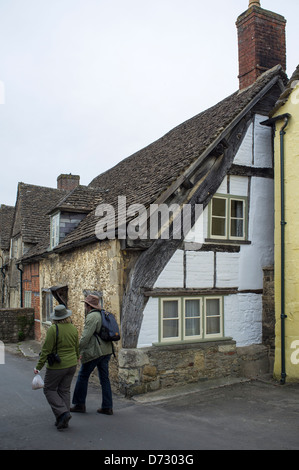 Touristen gehen vorbei an Half Fachwerk Gebäude Lacock Village Stockfoto