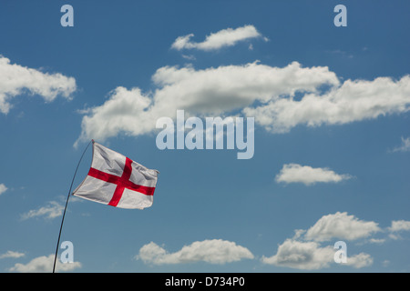 Englische Flagge vor dem Hintergrund eines blauen Himmels mit flauschigen weißen Wolken Stockfoto