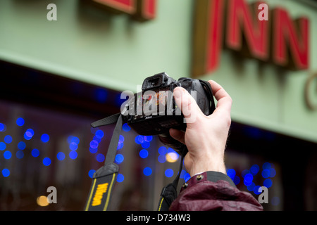 Ein Mann hält eine Nikon-Kamera, eine Löwe-Tanz-Performance beim chinesischen Neujahrsfest in London Chinatown aufnehmen Stockfoto