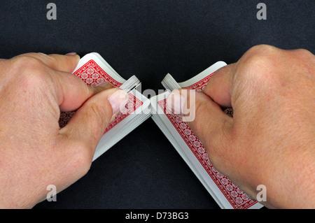 Frau, die ein Kartenspiel vor einem schwarzen Hintergrund mischt. Stockfoto