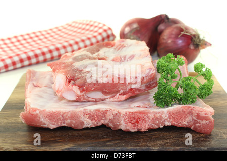 Rindfleisch-spare-Ribs mit Petersilie und Zwiebeln auf einem Holzbrett vor hellem Hintergrund Stockfoto