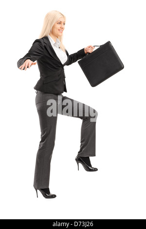 In voller Länge Portrait von eine Geschäftsfrau hält eine Aktentasche und versucht, die Balance, isoliert auf weißem Hintergrund zu halten Stockfoto