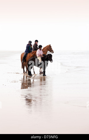 Drei Frauen Reiten am Holkham Beach, Norfolk Küste, East Anglia UK Stockfoto