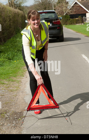 Weiblichen Autofahrer ein rotes Warndreieck hinter ihrem Auto Außerbetriebnahme Stockfoto