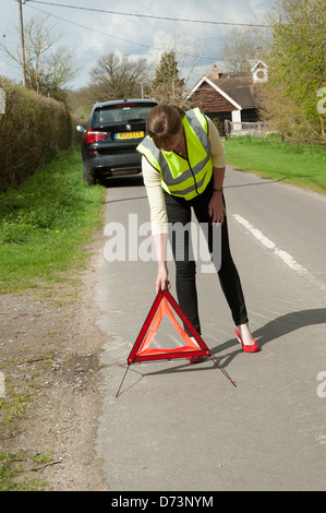 Weiblichen Autofahrer ein rotes Warndreieck hinter ihrem Auto Außerbetriebnahme Stockfoto