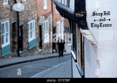 Ein Mann geht auf steilen Hügel, Lincoln, einer beliebten touristischen Straße in der historischen Stadt von Lincoln, Lincolnshire, England. Stockfoto