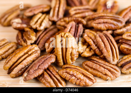 Horizontale Foto von leicht geröstete Pekannüsse mit Fokus stehenden Pecan vor Haufen auf Naturholz Stockfoto