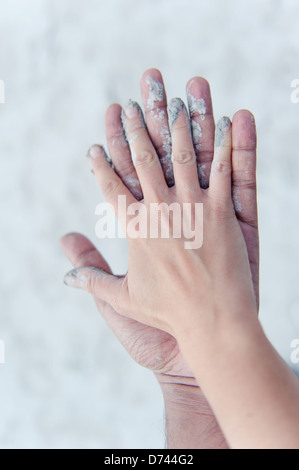 Ein Mann und Womans Hände berühren, bedeckt in weißen, grauen Ton. Stockfoto