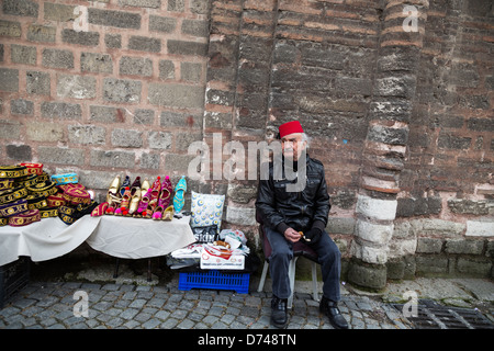 Mann trägt einen Fez mit Souvenirs auf der Straße in Fener, Istanbul, Türkei. Stockfoto