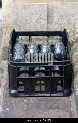 Kiste mit Milchcreme neun leere Milchflaschen aus Glas vor der Haustür in Großbritannien Stockfoto