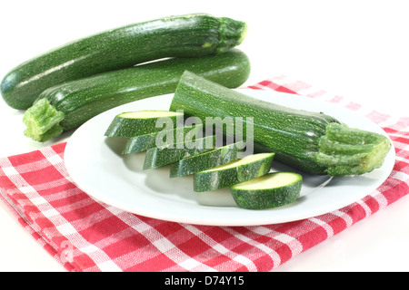 Frische in Scheiben geschnittene Zucchini auf einem Teller mit Serviette vor hellem Hintergrund Stockfoto