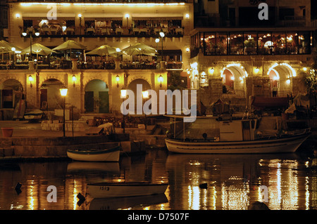 Blick auf die Boote und beleuchteten Restaurants in der Nacht in Spinola Bay Teil von St. Julian's eine Stadt, die in der zentralen Region von Malta Stockfoto