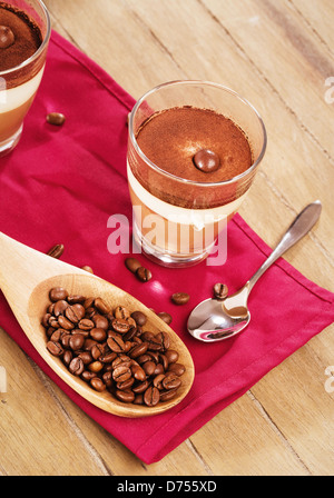 Tiramisu Dessert auf hölzernen Hintergrund mit Kaffeebohnen in einem Holzlöffel Stockfoto