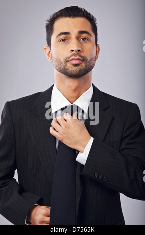 Porträt eines zuversichtlich jungen Geschäftsmann Festsetzung seiner Krawatte Stockfoto