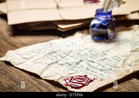 Tintenfass mit blauer Tinte Andsealing Wachs auf dem Hintergrund der Vintage Buchstaben Stockfoto