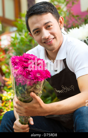 Freundliche asiatische Florist oder Verkäufer in einem Blumenladen mit einem Blumenstrauß Stockfoto