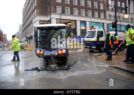 Arbeiter säubern herauf die Straße nach dem Platzen einer Wasserleitung außerhalb der Primark-Store auf der Oxford Street, London, am 20. Januar 2012. Stockfoto