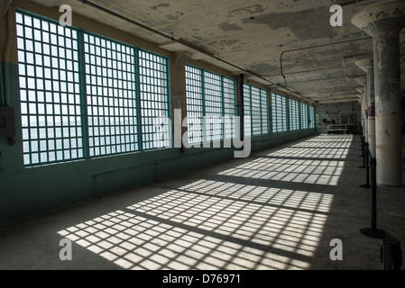 SAN FRANCISCO, Kalifornien: Das Sonnenlicht wirft scharfe Schatten aus den Bars auf die Fenster des Industries Building im ehemaligen Gefängniskomplex Alcatraz in der San Francisco Bay. Alcatraz ist bekannt für seine berüchtigten Häftlinge und die Gerüchte Unausweichlichkeit. Heute ist Alcatraz eine bedeutende Touristenattraktion und ein National Park Service-Standort, der Einblicke in das Gefängnissystem und historische Ereignisse des 20. Jahrhunderts bietet. Stockfoto