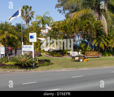 Mann mit Reiten-auf Rasenmäher, mähen Rasen im grossen 4 Maroochy Palmen Caravan Park in Maroochydore, Sunshine Coast, Queensland, Australien Stockfoto