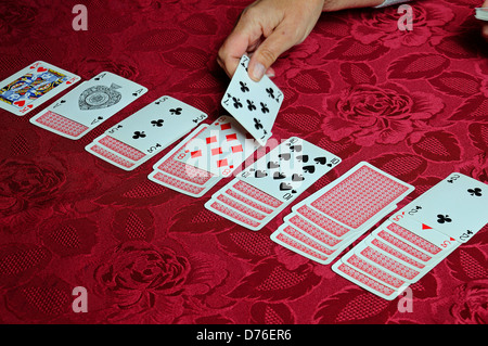 Frau spielt Geduld vor einem roten Hintergrund. Stockfoto