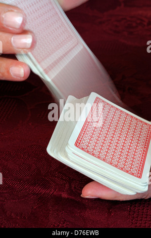 Frau, die ein Kartenspiel mit Spielkarten mischt, die die Kartenbewegung zeigen. Stockfoto