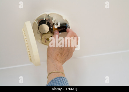 UK Seniorin Batteriewechsel in einen Rauchmelder Stockfoto