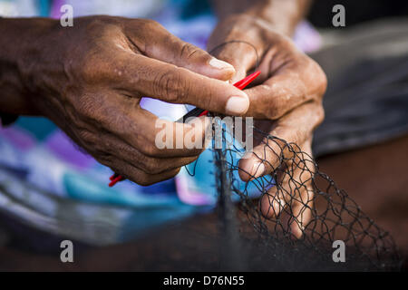 30. April 2013 - Mahachai, Samut Sakhon, Thailand - Reparaturen ein burmesische Arbeiter ein Fischernetz im Hafen Mahachai, Samut Sakhon Provinz, Thailand. Die thailändischen Fischwirtschaft ist stark abhängig von Birma und kambodschanischen Migranten. Burmesische Migranten Mannschaft viele der Fischerboote, die Segel aus Samut Sakhon und Mitarbeiter vieler die Fisch verarbeitende Betriebe in Samut Sakhon etwa 45 Meilen südlich von Bangkok. Migranten zahlen so viel $700 (US) jeweils von der burmesischen Grenze nach Samut Sakhon für Jobs geschmuggelt werden, die weniger als $5,00 (U.S.) pro Tag zu zahlen. Es gab auch Berichte, die einige birmanische Arbeiter sind Stockfoto