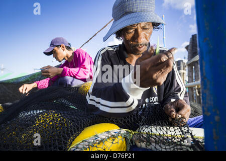 30. April 2013 - Mahachai, Samut Sakhon, Thailand - Burma Arbeiter reparieren Fischernetze in Port Mahachai, Samut Sakhon Provinz, Thailand. Die thailändischen Fischwirtschaft ist stark abhängig von Birma und kambodschanischen Migranten. Burmesische Migranten Mannschaft viele der Fischerboote, die Segel aus Samut Sakhon und Mitarbeiter vieler die Fisch verarbeitende Betriebe in Samut Sakhon etwa 45 Meilen südlich von Bangkok. Migranten zahlen so viel $700 (US) jeweils von der burmesischen Grenze nach Samut Sakhon für Jobs geschmuggelt werden, die weniger als $5,00 (U.S.) pro Tag zu zahlen. Es gab auch Berichte, die einige birmanische Arbeiter sind ein Stockfoto