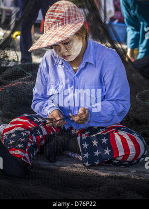 30. April 2013 - Mahachai, Samut Sakhon, Thailand - eine burmesische Arbeiter mit Thanaka Pulver auf ihrem Gesicht Reparaturen ein Fischernetz im Hafen Mahachai, Samut Sakhon Provinz, Thailand. Die thailändischen Fischwirtschaft ist stark abhängig von Birma und kambodschanischen Migranten. Burmesische Migranten Mannschaft viele der Fischerboote, die Segel aus Samut Sakhon und Mitarbeiter vieler die Fisch verarbeitende Betriebe in Samut Sakhon etwa 45 Meilen südlich von Bangkok. Migranten zahlen so viel $700 (US) jeweils von der burmesischen Grenze nach Samut Sakhon für Jobs geschmuggelt werden, die weniger als $5,00 (U.S.) pro Tag zu zahlen. Es gab auch Bericht Stockfoto