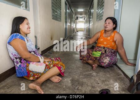 30. April 2013 - Mahachai, Samut Sakhon, Thailand - birmanische Frauen in den Flur ihres Mehrfamilienhauses in der thailändischen Fischerei Hafen Mahachai entspannen. Die thailändischen Fischwirtschaft ist stark abhängig von Birma und kambodschanischen Migranten. Burmesische Migranten Mannschaft viele der Fischerboote, die Segel aus Samut Sakhon und Mitarbeiter vieler die Fisch verarbeitende Betriebe in Samut Sakhon etwa 45 Meilen südlich von Bangkok. Migranten zahlen so viel $700 (US) jeweils von der burmesischen Grenze nach Samut Sakhon für Jobs geschmuggelt werden, die weniger als $5,00 (U.S.) pro Tag zu zahlen. Auch gab es Berichte, dass einige birmanische Arbeiter Stockfoto