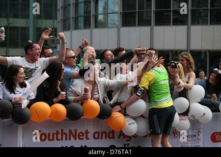 Fans feiern mit einem Läufer im Wettbewerb mit den 2013 Virgin London-Marathon für einen guten Zweck Stockfoto