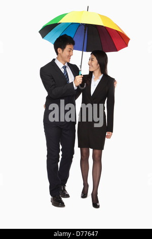 Unternehmer und Unternehmerinnen unter bunten Regenschirm spazieren Stockfoto