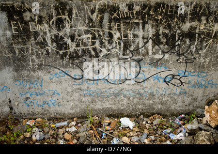 Grafity und Müll neben einer Wand Stockfoto