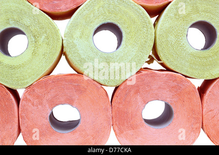 Stapel von gelben und rosa Toilettenpapier auf weißem Hintergrund Stockfoto