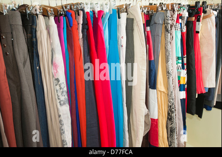 Mehrfarbige Verschiedenes von hängender Kleidung auf Kleiderbügeln und Schiene in einem Geschäft Stockfoto