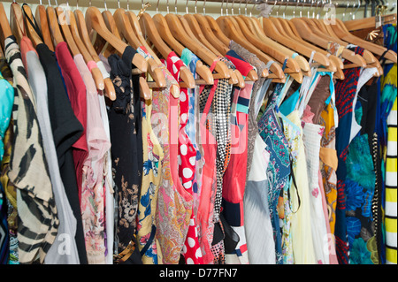 Mehrfarbige Verschiedenes von hängender Kleidung auf Kleiderbügeln und Schiene in einem Geschäft Stockfoto