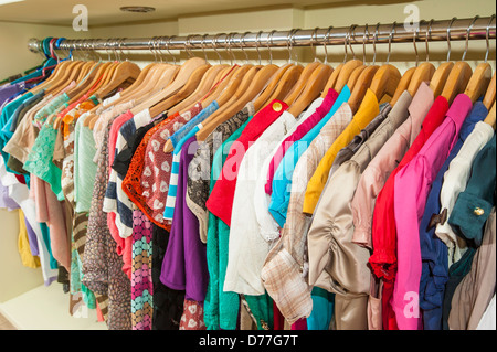 Mehrfarbige Verschiedenes von hängender Kleidung auf Kleiderbügeln und Schiene in einem Geschäft Stockfoto