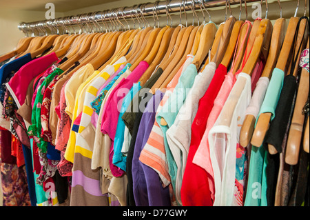 Mehrfarbige Verschiedenes von hängender Kleidung auf Kleiderbügeln und Schiene in einem Geschäft Stockfoto