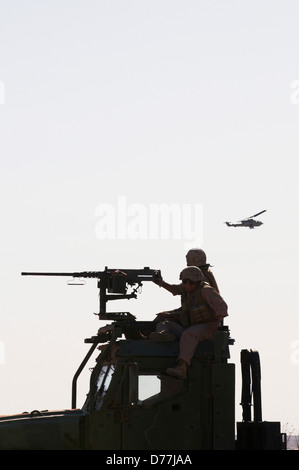 Silhouetten U.S. Marines bereit, M2 Kaliber.50 Maschinengewehr US Marine Corps AH-1W Pkw in Ferne Feuer Stockfoto