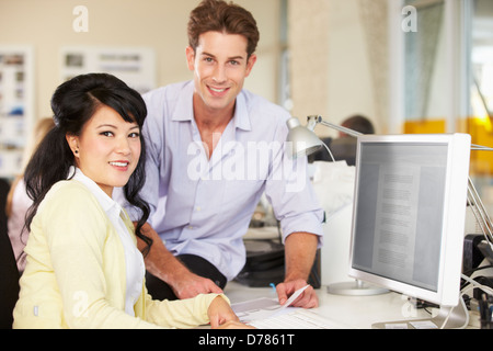 Arbeiter am Schreibtisch im geschäftigen Kreativbüro Stockfoto