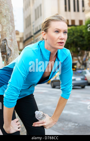 Frau ruht beim städtischen Straße entlang laufen Stockfoto