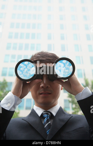 Junger Geschäftsmann mit Fernglas und Blick in die Ferne Stockfoto