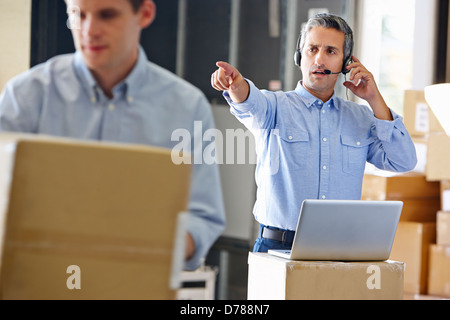 Manager mit Kopfhörer im Auslieferungslager Stockfoto