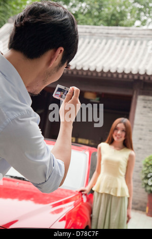 Junger Mann, ein Bild von seiner Freundin und Auto Stockfoto