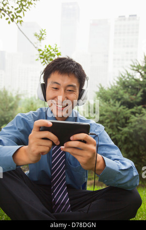 Junger Geschäftsmann anhören von Musik auf seinem MP4-player Stockfoto