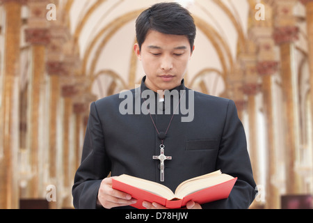 Priester, die Bibel in der Kirche zu betrachten Stockfoto