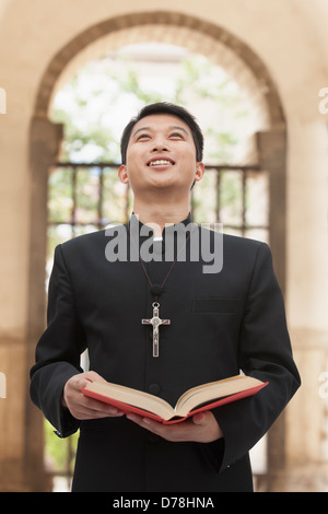 Junger Priester Blick in Himmel vor der Tür Stockfoto